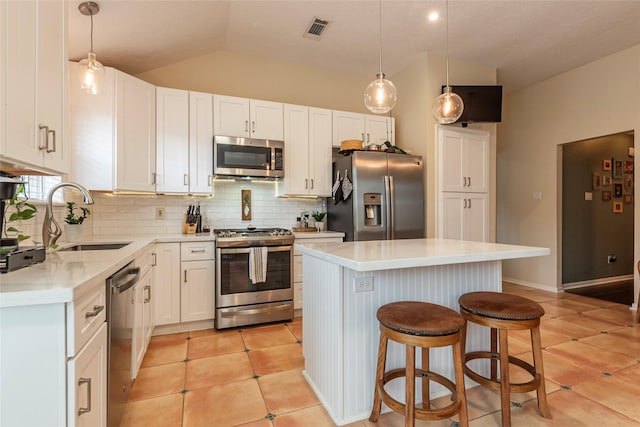 kitchen with visible vents, a center island, a breakfast bar, stainless steel appliances, and a sink