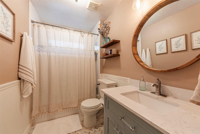 bathroom with vanity, toilet, visible vents, and a textured ceiling