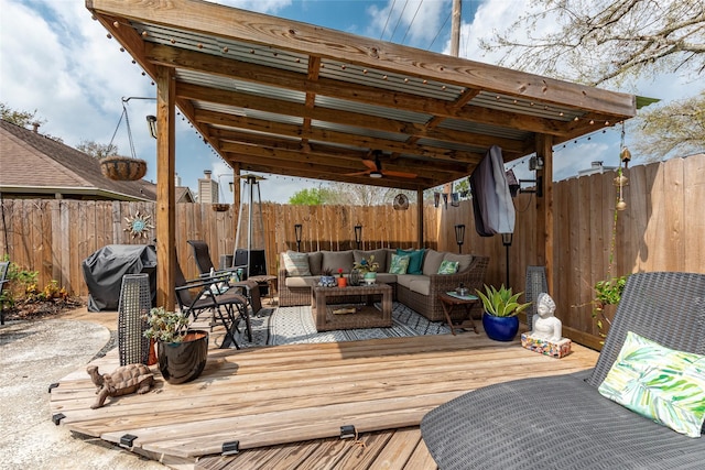 wooden terrace featuring an outdoor living space, a fenced backyard, and a grill