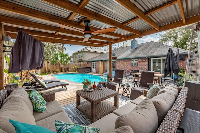 view of swimming pool with an outdoor living space, a fenced in pool, a fenced backyard, and a ceiling fan