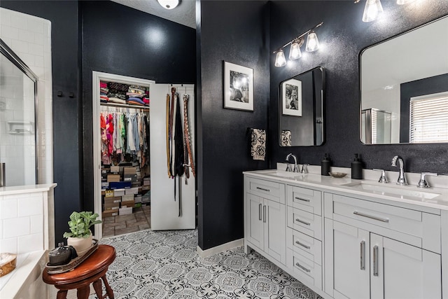 bathroom featuring a tile shower, a spacious closet, and a sink