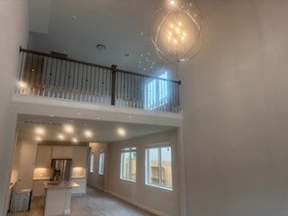 unfurnished living room featuring light wood-style floors, baseboards, and a towering ceiling