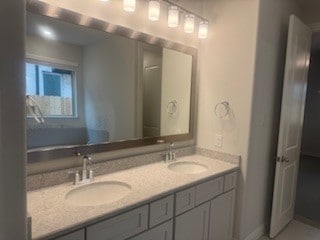 full bath featuring double vanity, baseboards, and a sink