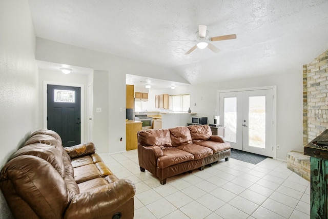 living room featuring a ceiling fan, a textured ceiling, french doors, light tile patterned floors, and lofted ceiling