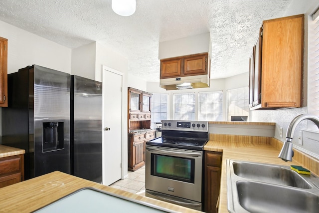 kitchen featuring stainless steel appliances, a sink, light countertops, under cabinet range hood, and a textured ceiling