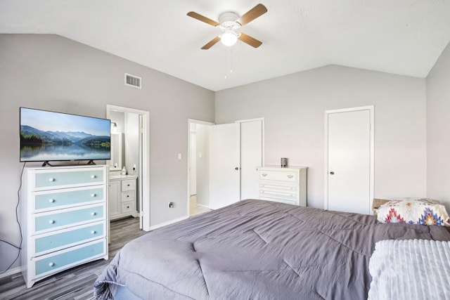 bedroom featuring wood finished floors, visible vents, ceiling fan, vaulted ceiling, and ensuite bathroom