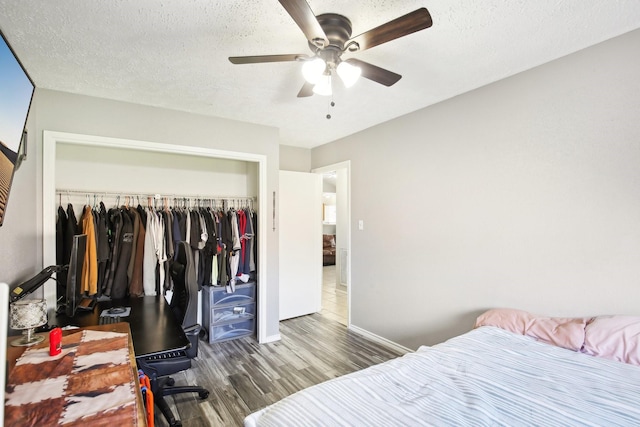 bedroom with a closet, baseboards, a textured ceiling, and wood finished floors