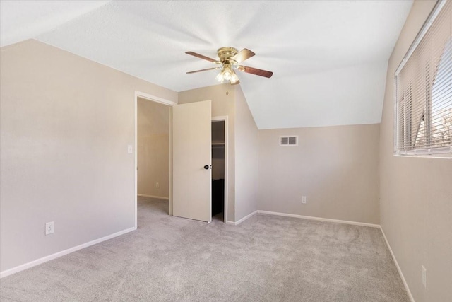 additional living space with lofted ceiling, light carpet, visible vents, and ceiling fan