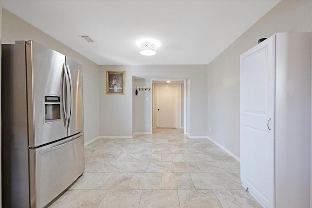 kitchen featuring visible vents, stainless steel fridge, and baseboards