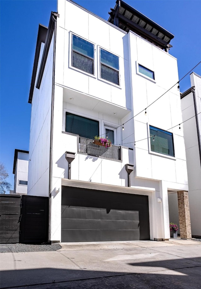 contemporary house with stucco siding, a balcony, and an attached garage