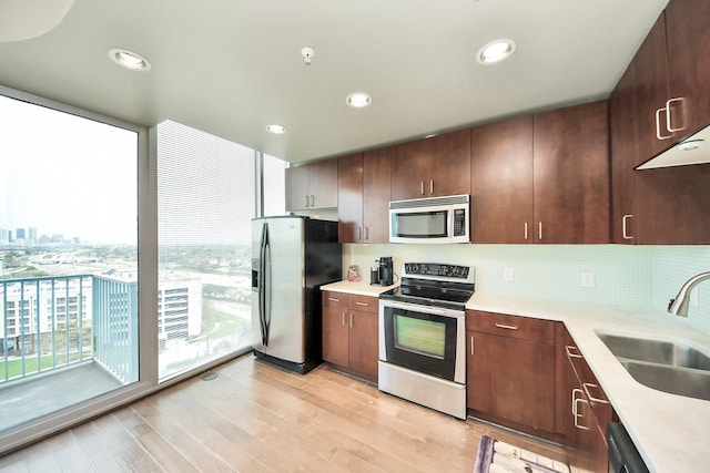 kitchen featuring a sink, stainless steel appliances, decorative backsplash, and light countertops