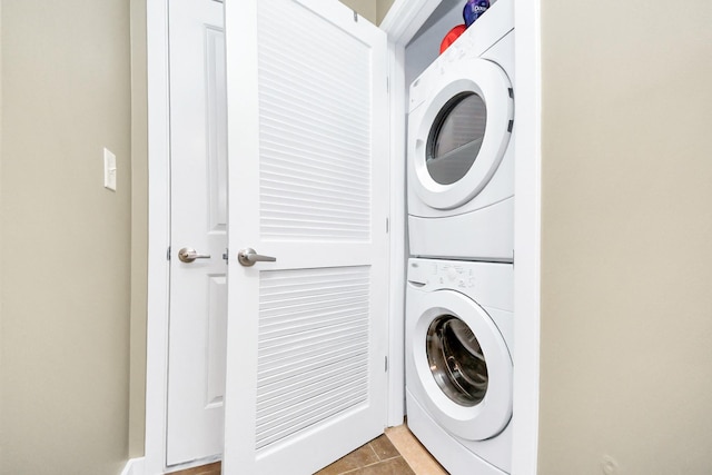 laundry area featuring tile patterned flooring and stacked washing maching and dryer