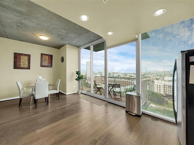 dining room with baseboards, expansive windows, recessed lighting, wood finished floors, and a view of city