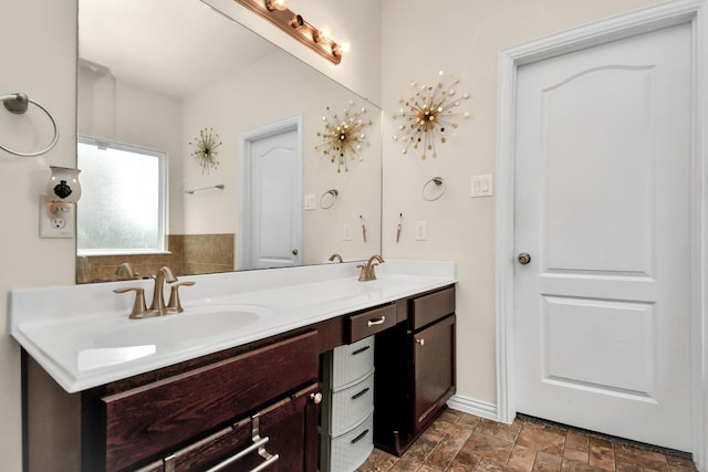 bathroom featuring double vanity, stone finish floor, and a sink