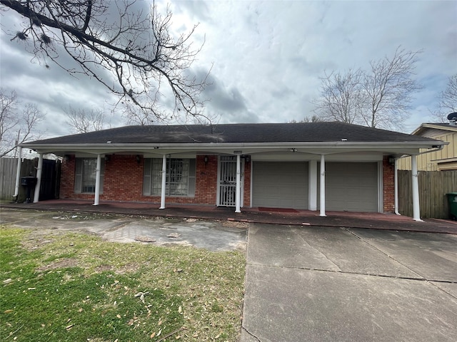 ranch-style home featuring fence, covered porch, concrete driveway, an attached garage, and brick siding