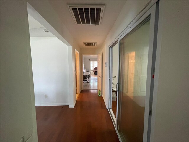 corridor with dark wood finished floors, visible vents, and baseboards