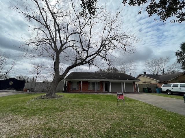 view of front of house with brick siding, a front lawn, fence, concrete driveway, and a garage