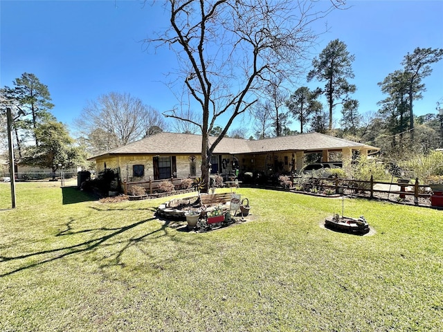 rear view of property with a lawn, fence, and stone siding