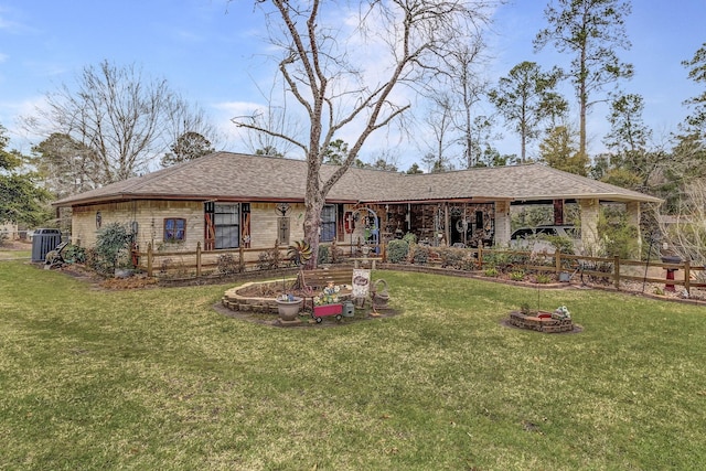 rear view of property with central air condition unit, fence, an outdoor fire pit, a yard, and roof with shingles