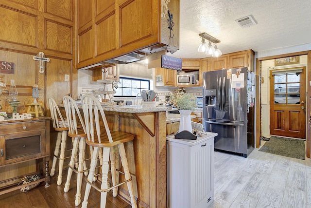 kitchen featuring a peninsula, visible vents, light wood-type flooring, and stainless steel appliances