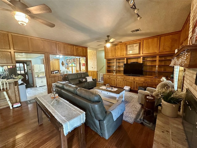 living area with visible vents, a brick fireplace, wood finished floors, and a ceiling fan