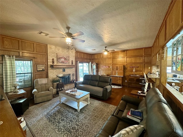 living area with a brick fireplace, wood walls, dark wood-style flooring, and a decorative wall