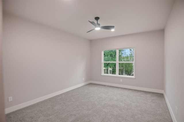 empty room with carpet flooring, a ceiling fan, and baseboards