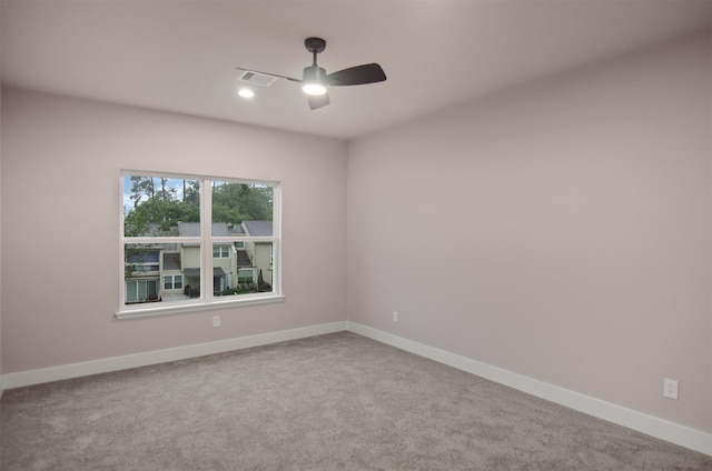 carpeted empty room with visible vents, baseboards, and ceiling fan