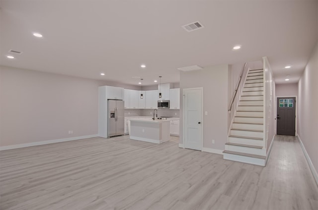 unfurnished living room with light wood-type flooring, a sink, recessed lighting, stairway, and baseboards