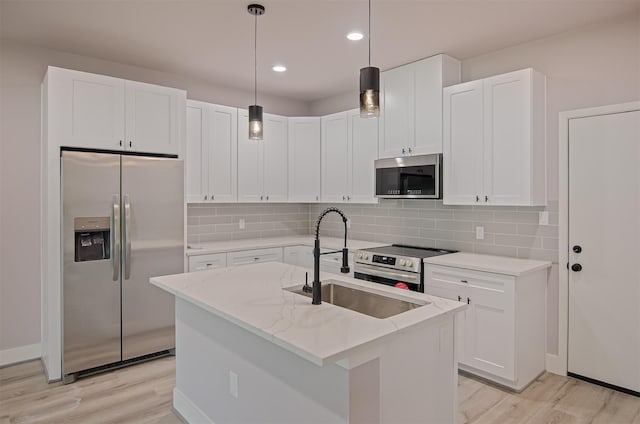 kitchen with a sink, stainless steel appliances, light wood-type flooring, and tasteful backsplash