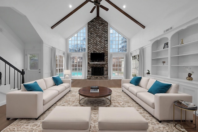 living area with light wood-type flooring, visible vents, high vaulted ceiling, and a brick fireplace