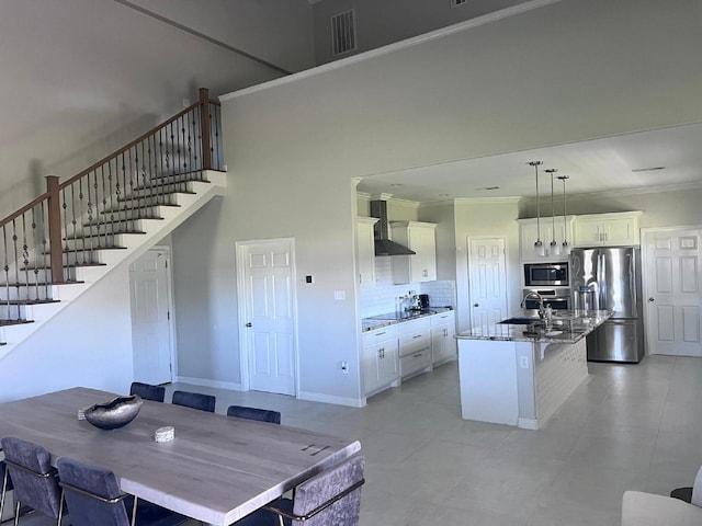 kitchen with visible vents, appliances with stainless steel finishes, wall chimney exhaust hood, and ornamental molding