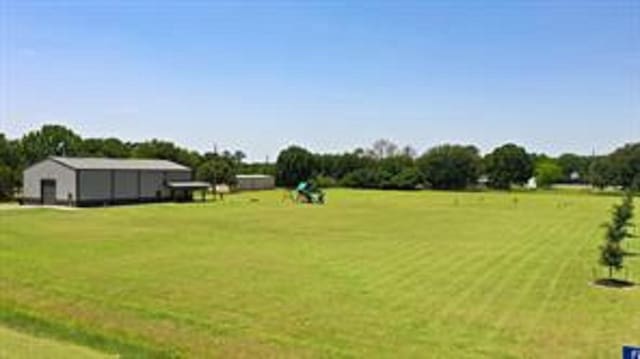 view of yard with an outbuilding, a rural view, and an outdoor structure