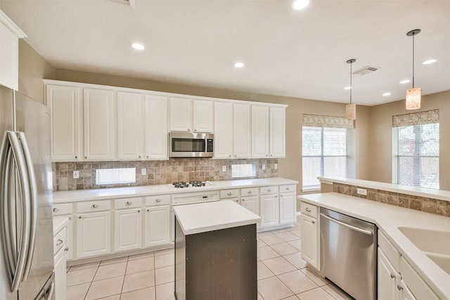 kitchen featuring light tile patterned floors, stainless steel appliances, decorative backsplash, light countertops, and decorative light fixtures