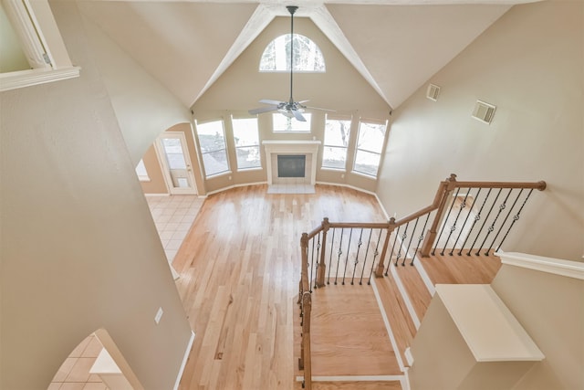 18 Valley Mead Pl, Conroe, TX 77384 - stairs with ceiling fan, wood finished floors, high vaulted ceiling, and a glass covered fireplace