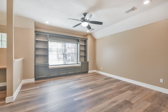 interior space with baseboards, visible vents, light wood-style flooring, ceiling fan, and vaulted ceiling