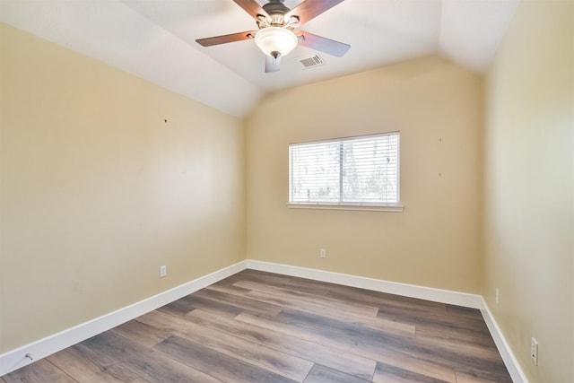 unfurnished room featuring visible vents, wood finished floors, baseboards, and vaulted ceiling