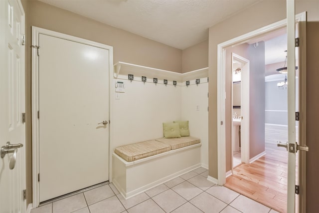 mudroom with light tile patterned flooring, a textured ceiling, and baseboards