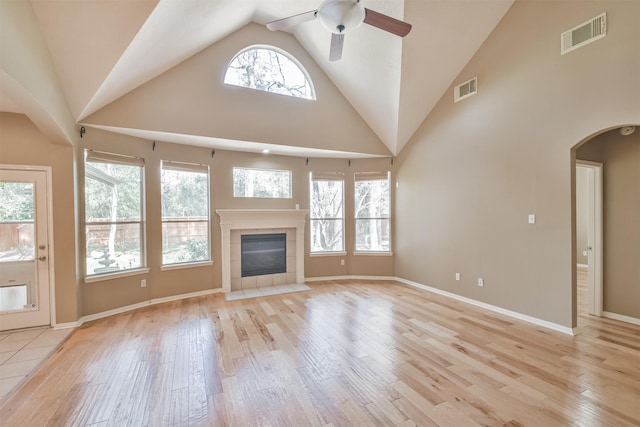 18 Valley Mead Pl, Conroe, TX 77384 - unfurnished living room with light wood-style floors, a ceiling fan, high vaulted ceiling, arched walkways, and a fireplace