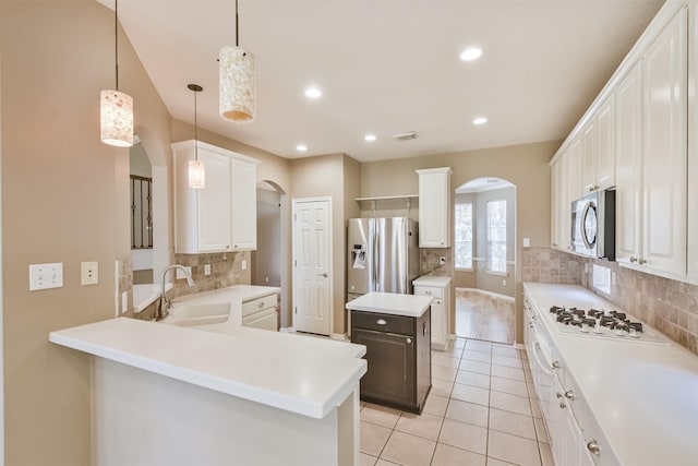 kitchen featuring a sink, stainless steel appliances, arched walkways, and decorative backsplash