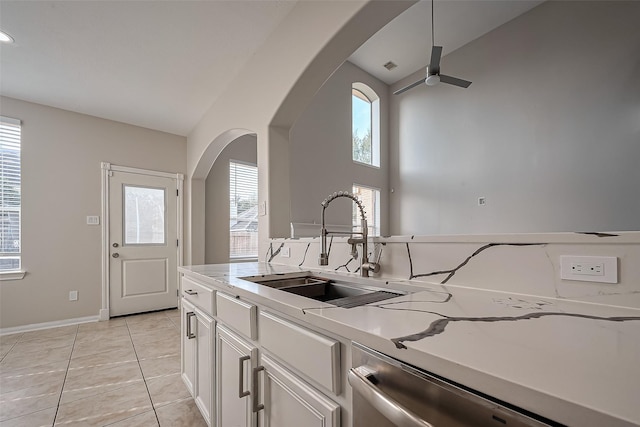 kitchen with ceiling fan, light countertops, light tile patterned floors, arched walkways, and a sink