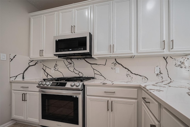 kitchen with backsplash, stainless steel gas range, and white cabinetry