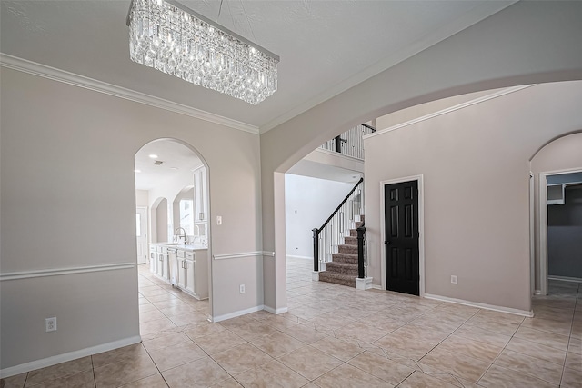 unfurnished room with light tile patterned floors, a sink, arched walkways, and ornamental molding