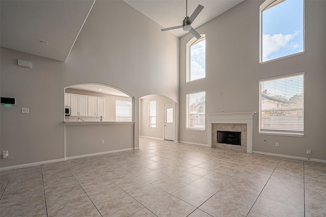 unfurnished living room with light tile patterned flooring, baseboards, a wealth of natural light, and ceiling fan