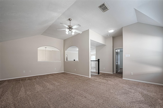 unfurnished room featuring visible vents, a ceiling fan, carpet floors, baseboards, and vaulted ceiling