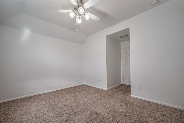 carpeted empty room featuring visible vents, baseboards, ceiling fan, and vaulted ceiling