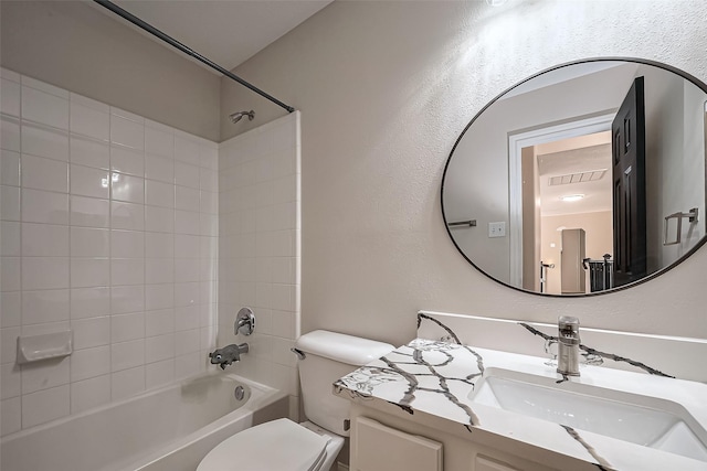 bathroom with toilet, vanity,  shower combination, and a textured wall