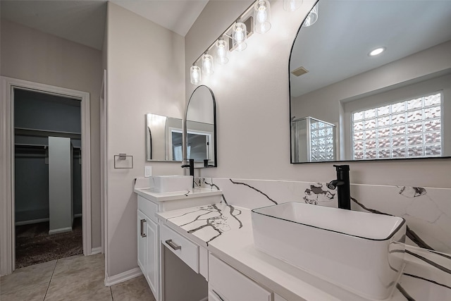 full bath featuring visible vents, double vanity, a stall shower, tile patterned floors, and a sink