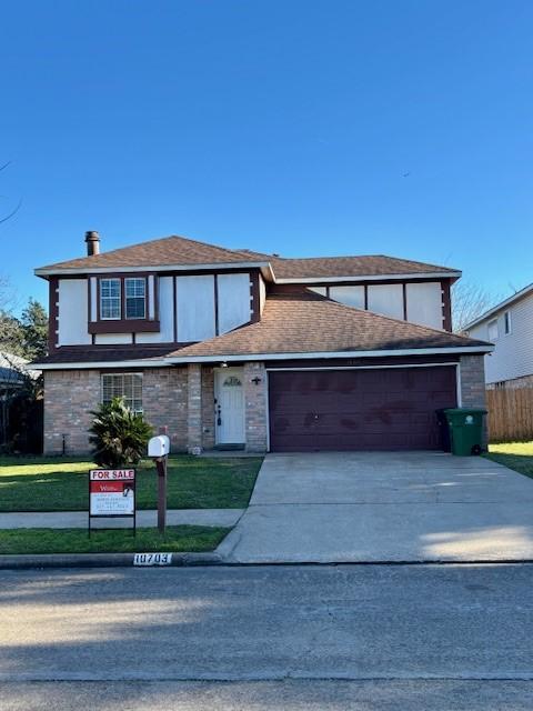 view of front of house with a front lawn, concrete driveway, an attached garage, and fence