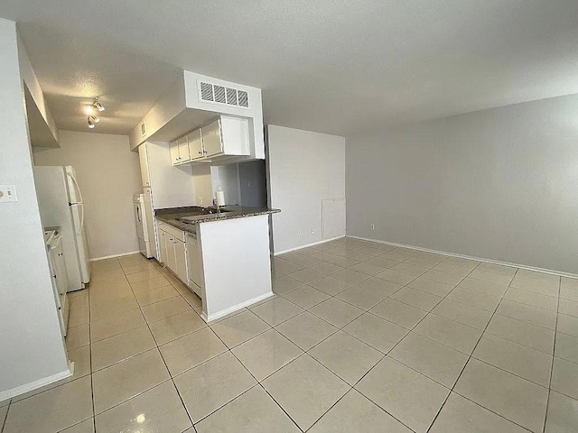 kitchen featuring visible vents, a sink, dark countertops, white cabinets, and light tile patterned floors